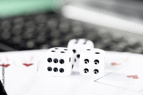 Online gaming platform, casino and gambling business. Cards, dice and multi-colored game pieces on laptop keyboard