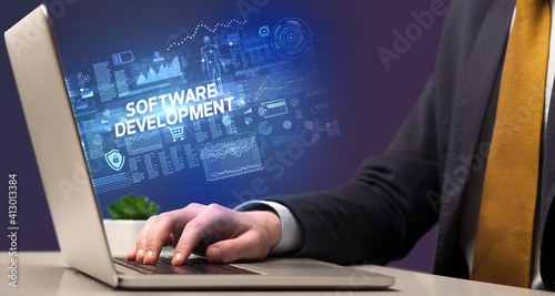 Businessman working on laptop with SOFTWARE DEVELOPMENT inscription, cyber technology concept