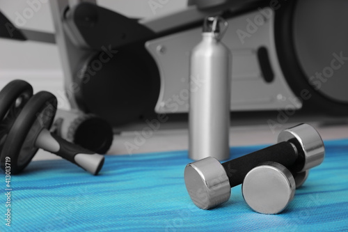 Dumbbells and sport equipment near elliptical machine in gym