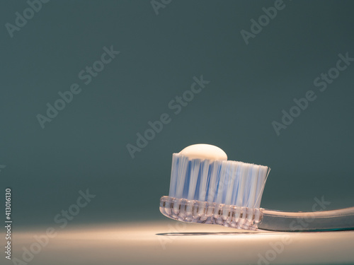 toothbrush with recommended amount of toothpaste equivalent to the size of a pea lit on gray background
