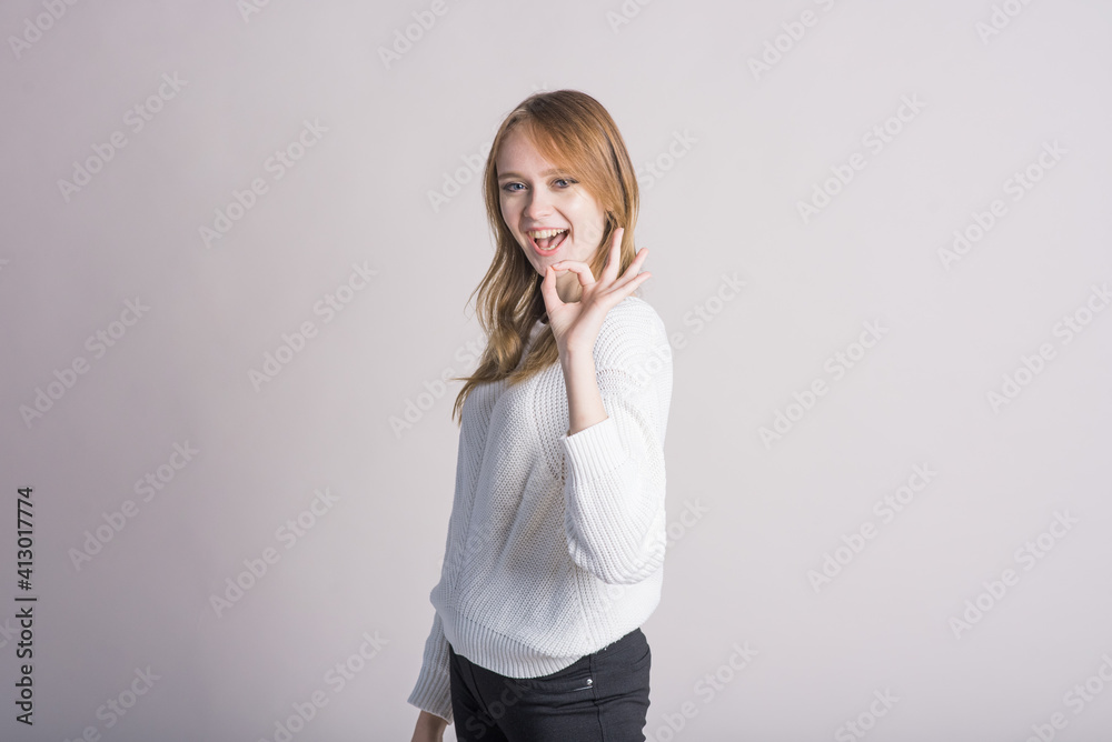 Portrait of a stylish girl on a white background in the studio who shows Okay Agree Portrait of a stylish girl on a white background in the studio who shows Okay Agree