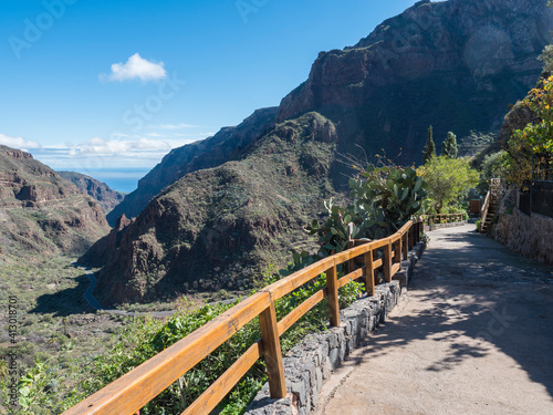 Barranco de Guayadeque ravine view from Montana de las Tierras with winding road towards ocean. Gran Canaria, Canary Island, Spain. Sunny day, blue sky, white clouds background photo