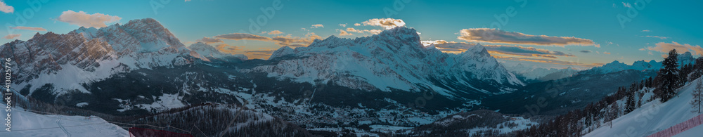 Early morning wide winter panorama of Valley around Cortina d'Ampezzo viewed from Tofana or ski piste above Cortina. Majestic mountains rising from the valley in sunrise.