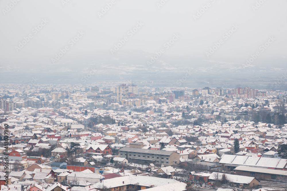High angle view of snow covered cityscape of Pirot, Serbia, on a misty, cloudy, murky winter day
