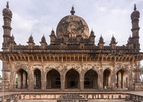 Vijayapura, Karnataka, India - November 8, 2013: West side of brown stone Ibrahim Rauza mausoleum fills entire frame under blue cloudscape.