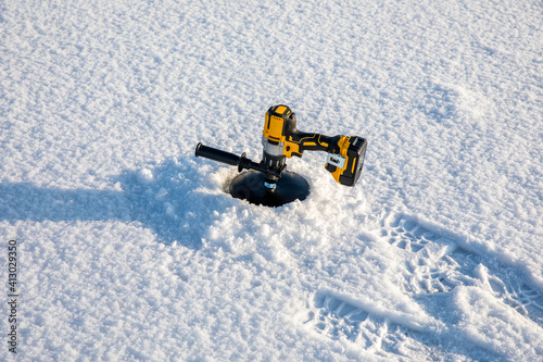 Electric auger left in an ice hole photo