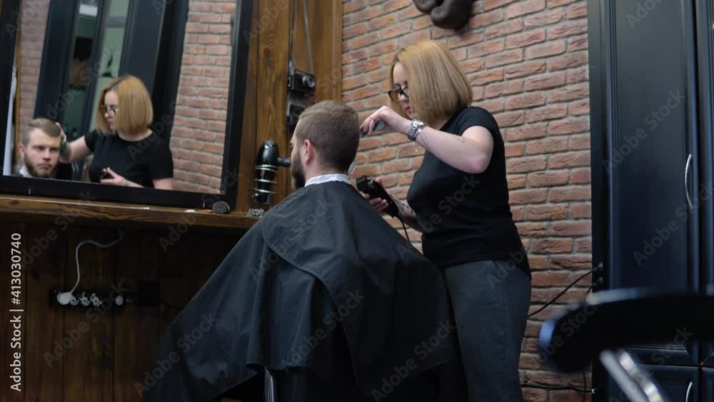 The client's hair is cut with a trimmer in a barbershop The client's hair is cut with a trimmer in a barbershop