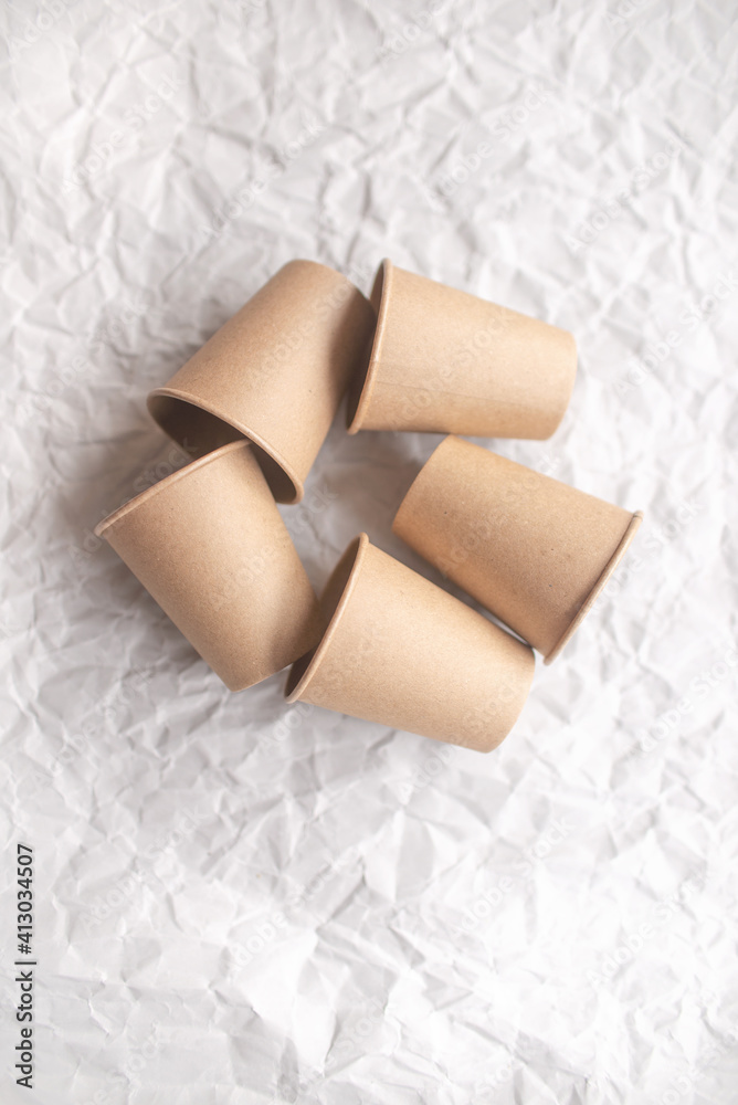 disposable kraft paper cups laid out on gray crumpled paper