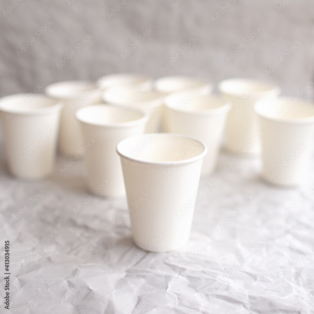 disposable cups made of white paper are laid out on gray crumpled paper disposable cups made of white paper are laid out on gray crumpled paper