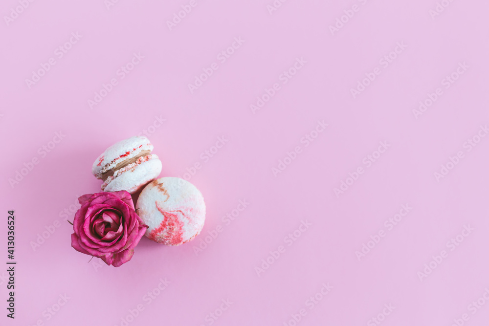 Tasty french macaroons with pink roses on a pink pastel background. Tasty french macaroons with pink roses on a pink pastel background.