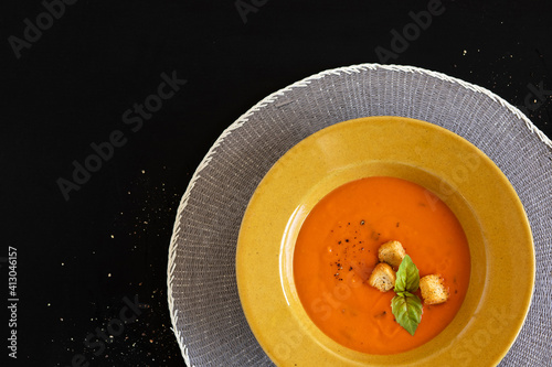 Obraz na plátně tomato soup with basil on black background, copy space, top view