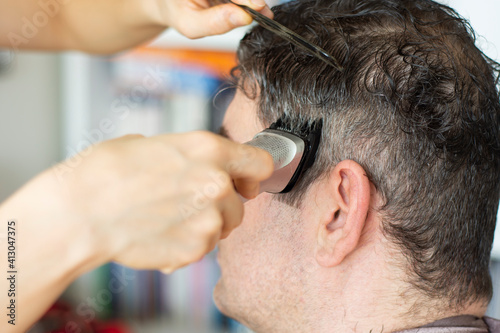 Young woman is cutting her husband's hair at home during the pandemic, stay at home