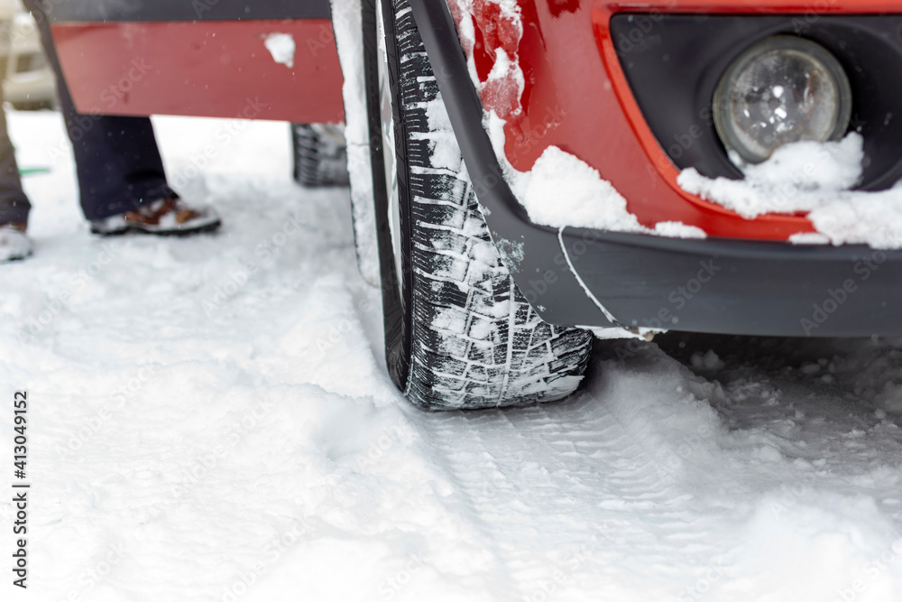 Photo of car tires on winter road covered with snow. Vehicle on snowy way in the morning at snowfall. Wheel of a car on a winter road in a blizzard. Snow covered car wheel. Winter tire. Copy space. Photo of car tires on winter road covered with snow. Vehicle on snowy way in the morning at snowfall. Wheel of a car on a winter road in a blizzard. Snow covered car wheel. Winter tire. Copy space.