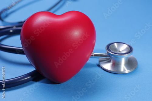 Red heart shape and stethoscope on blue background