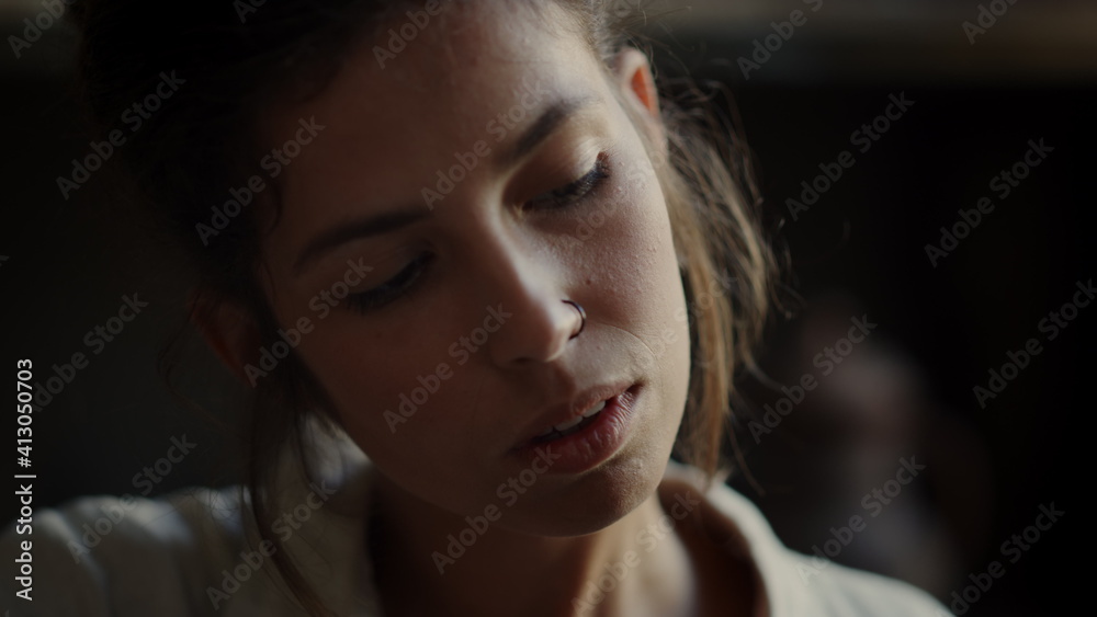 Focused woman examining something in workshop. Girl touching something in studio Focused woman examining something in workshop. Girl touching something in studio