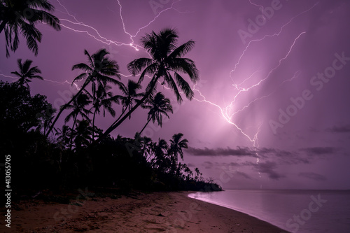 Fototapeta Naklejka Na Ścianę i Meble -  Dramatic Lightning strikes the ocean from a palm beach