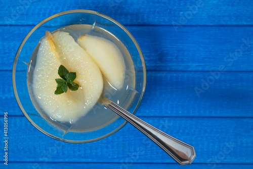 Fresh half Pears Served with sweet syrup and mint leaves. Blue background.
