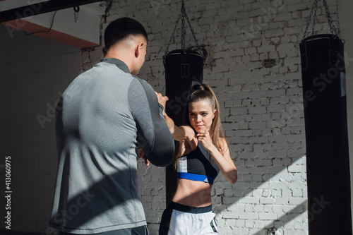 A young attractive boxing coach prepares a pretty girl for competition