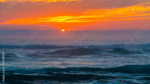 Sunrise at sea. The sun rises over the horizon of the sea and a new day begins. Panoramic sea landscape on sunset or sunrise with ocean waves and orange colorful clouds in sky.