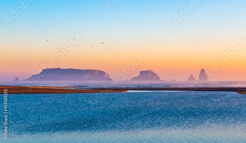 Mouth of the river Ter in the Mediterranean Sea with the Medes Islands and Estartit in the background. Panoramic sunrise landscape with the river flowing calmly. Morning lights with calm atmosphere. photo
