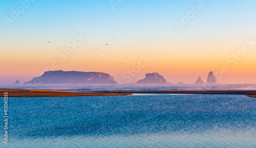 Mouth of the river Ter in the Mediterranean Sea with the Medes Islands and Estartit in the background. Panoramic sunrise landscape with the river flowing calmly. Morning lights with calm atmosphere. photo