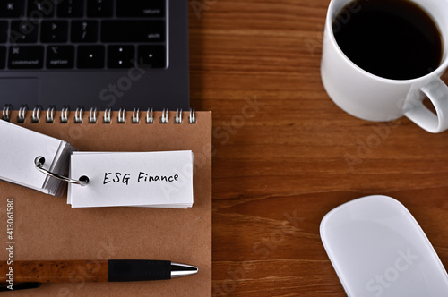 There s a cup of coffee  a laptop and a notebook with a word book on it that says ESG Finance.