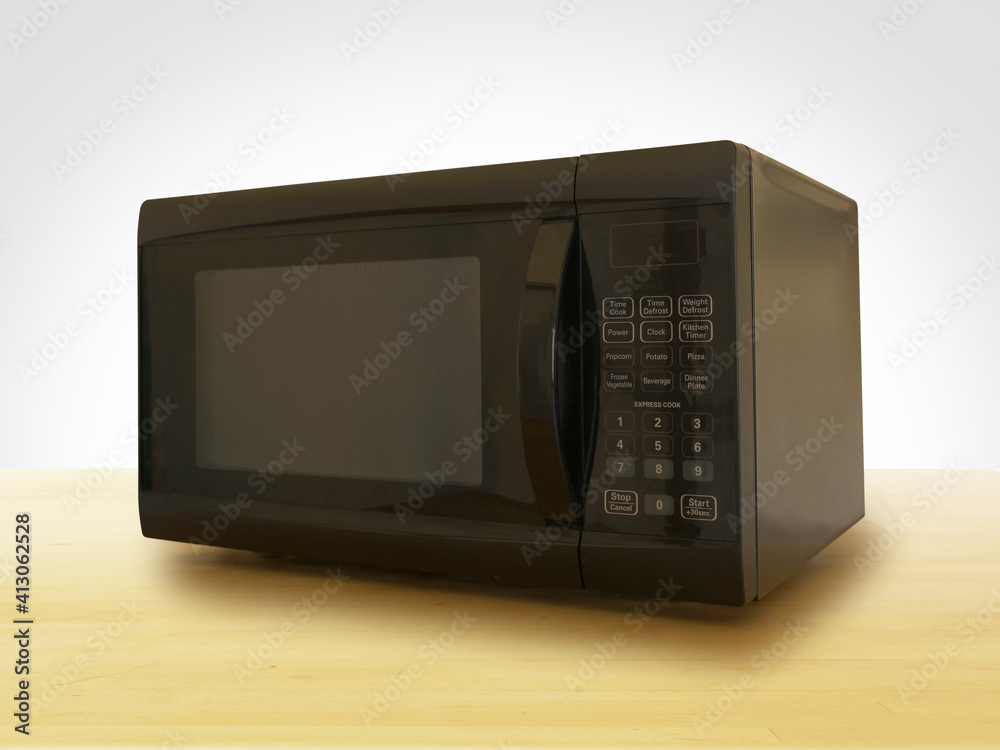 Fototapeta premium Black Microwave on Wooden Countertop with White Background