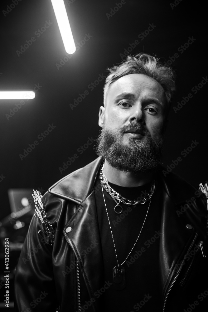 Fototapeta premium brutal portrait of a man musician with a beard and in black clothes on the background of musical instruments drums