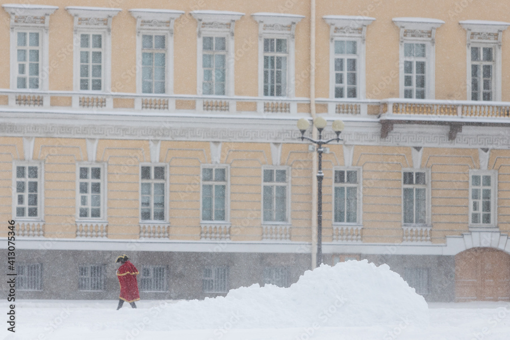 Actor in costume of Peter The Great walking on a square, high heaps of snow on background, walking on a deep, recently fallen snow. Winter time and heavy blizzard at St. Petersburg Russia