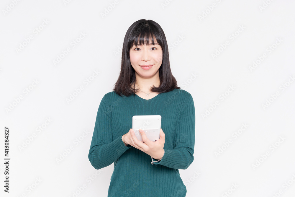 白背景の前に立って電卓を使う女性 白背景の前に立って電卓を使う女性