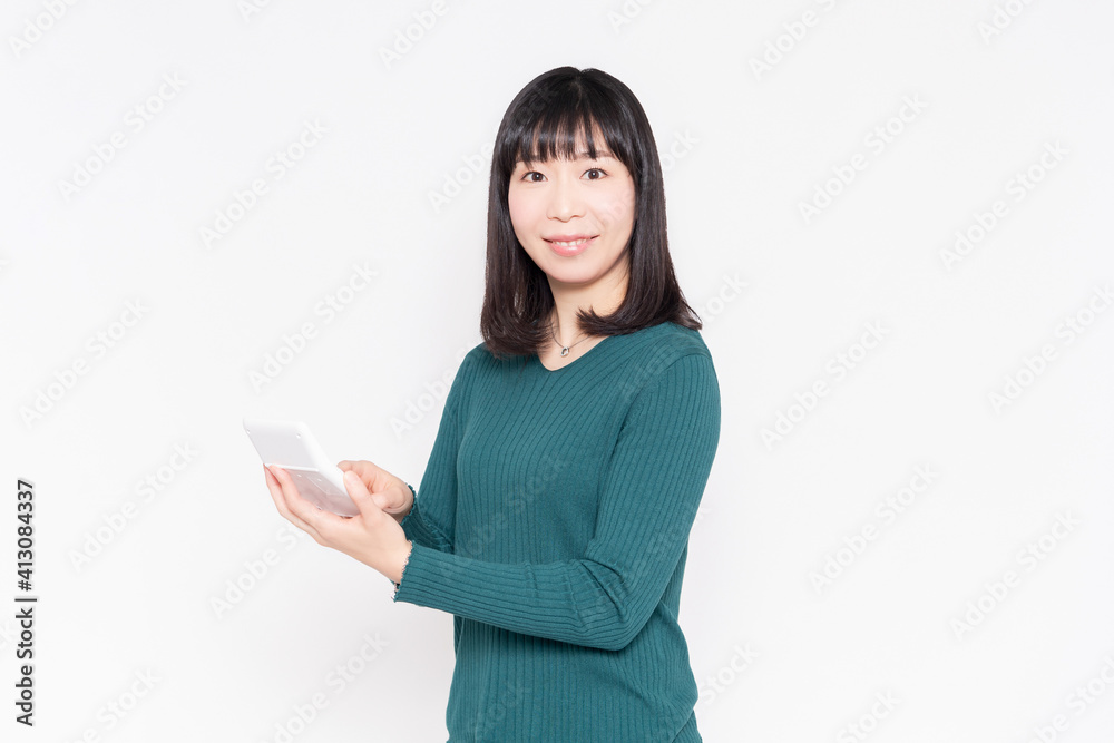 白背景の前に立って電卓を使う女性 白背景の前に立って電卓を使う女性