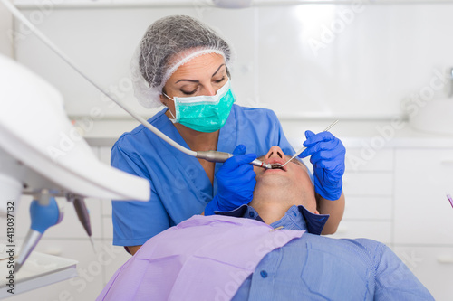 adult dentist checking teeth of patient male sitting in medical center