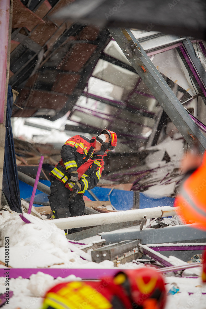Obraz premium The working moments of the search and rescue teams who were under the rubble in the roof collapse under the weight of snow. Firefighters inside a collapsed house are looking for survivors.