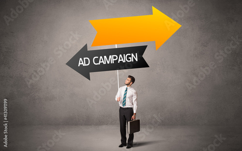 Young business person in casual holding road sign with AD CAMPAIGN inscription, business direction concept © ra2 studio