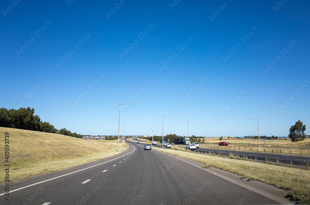View of a road merging to the highway at the outskirt of Melbourne's urban area. Background texture of the Australian motorway with some cars in the distance.  M31 Hume Freeway VIC Australia,