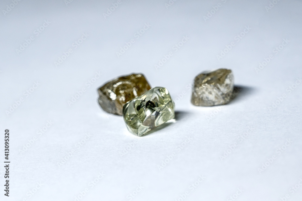 Three multi-colored diamonds lie on a white plastic surface Three multi-colored diamonds lie on a white plastic surface