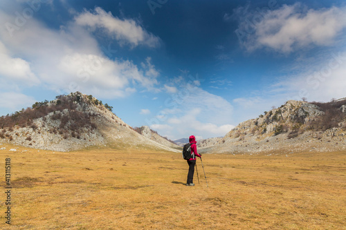 Beautiful scenery in the mountains with sharp limestome rocks, hiking path and April sky and showers, with cumulus clouds