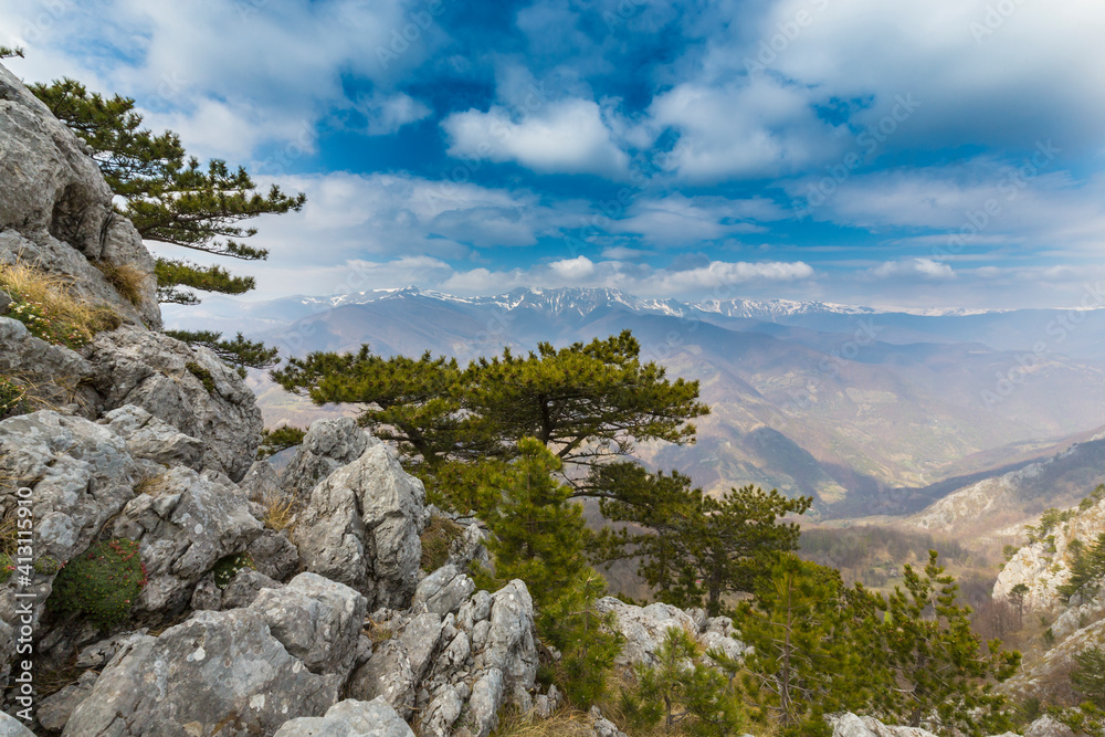 Beautiful scenery in the mountains with sharp limestome rocks, hiking path and April sky and showers, with cumulus clouds