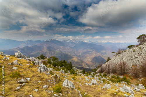 Beautiful scenery in the mountains with sharp limestome rocks, hiking path and April sky and showers, with cumulus clouds photo