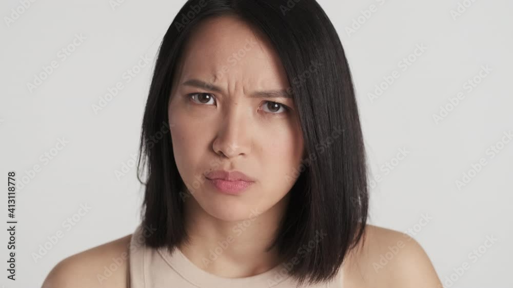 Close up angry Asian girl looking from eyebrows offended on boyfriend isolated over white background. Irate face expression