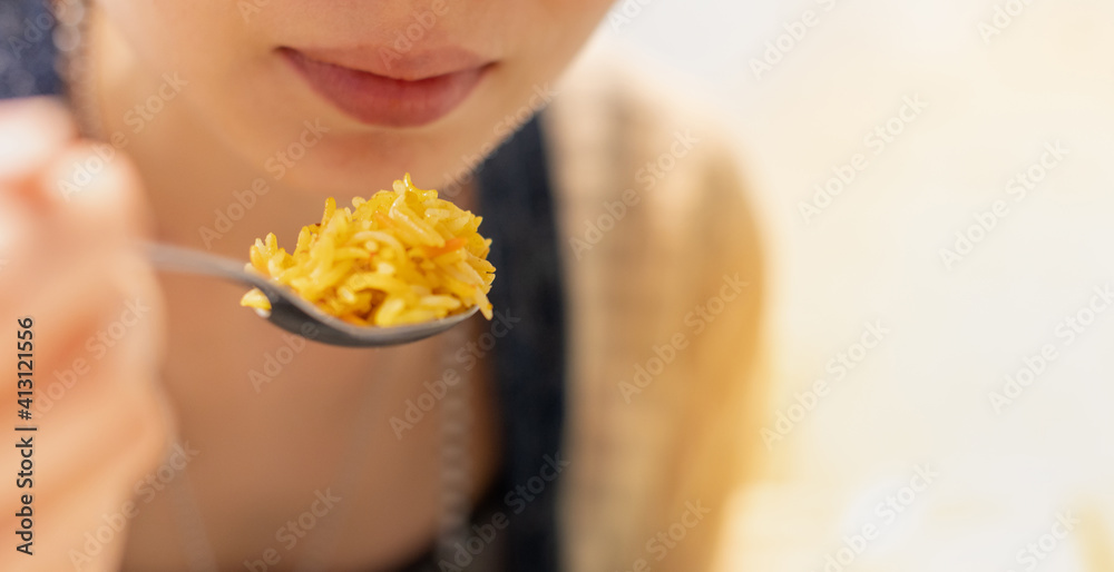 The Asian girl hand holding spoon and eating the egyptian curry fried rice food at the restaurant The Asian girl hand holding spoon and eating the egyptian curry fried rice food at the restaurant