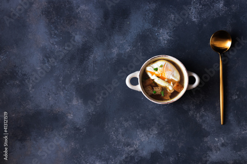 Garlic soup with roasted bread and poached egg. Top down view on dark background.