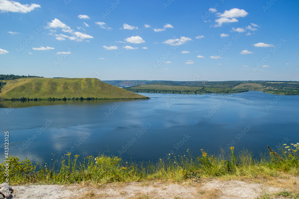 Beautiful panoramic view of a large lake among the hills on a sunny day. River and rocks landscape. Top view of Bakota Bay made by Dniester river. The Dniester Canyon in National Park Podilski Tovtry.