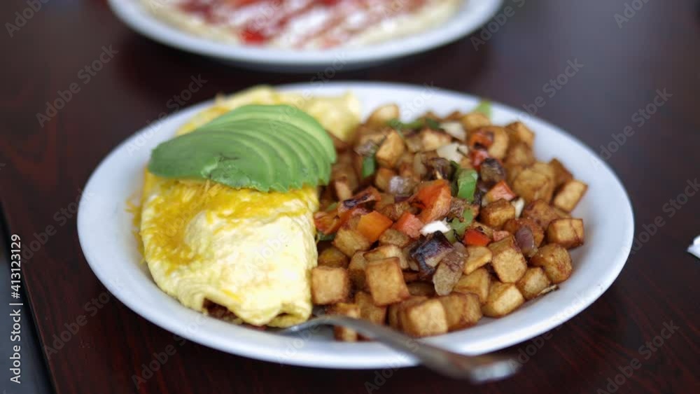 Omelette, roasted potatoes and avocado slices on a white plate Omelette, roasted potatoes and avocado slices on a white plate