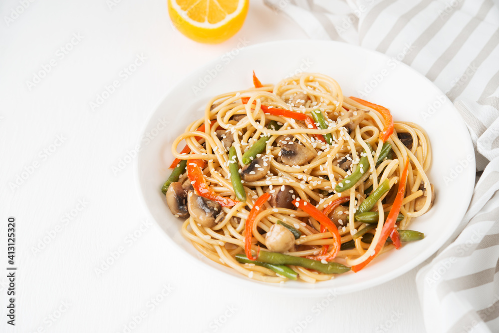 Noodles with vegetables (string beans, bell peppers, sesame seeds) and mushrooms in soy sauce, traditional Asian food Noodles with vegetables (string beans, bell peppers, sesame seeds) and mushrooms in soy sauce, traditional Asian food
