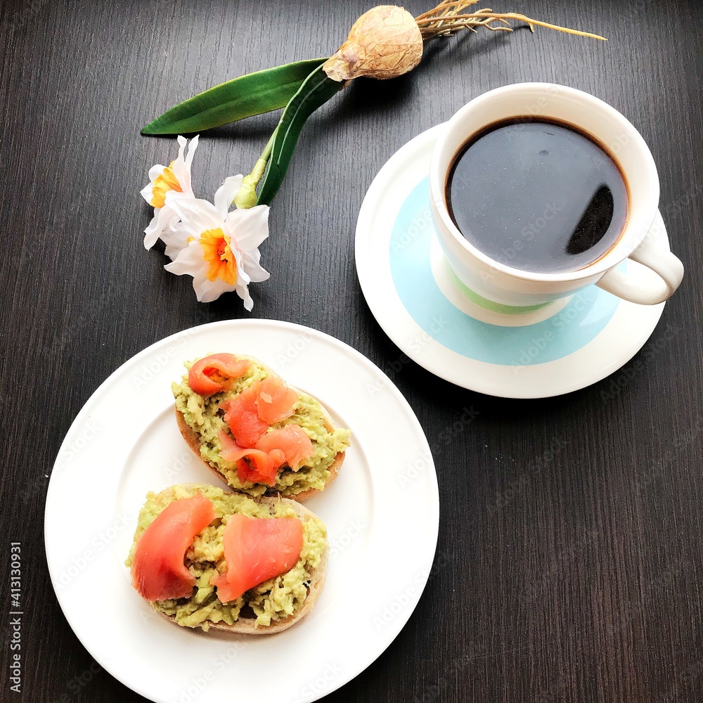 coffee and sandwiches with salmon and avocado on a plate. coffee and sandwiches with salmon and avocado on a plate.