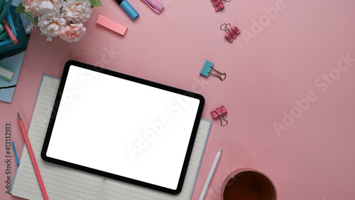 Above view of modern feminine  workspace with digital tablet  stylus pen  stationery  notebook and copy space on pink background.