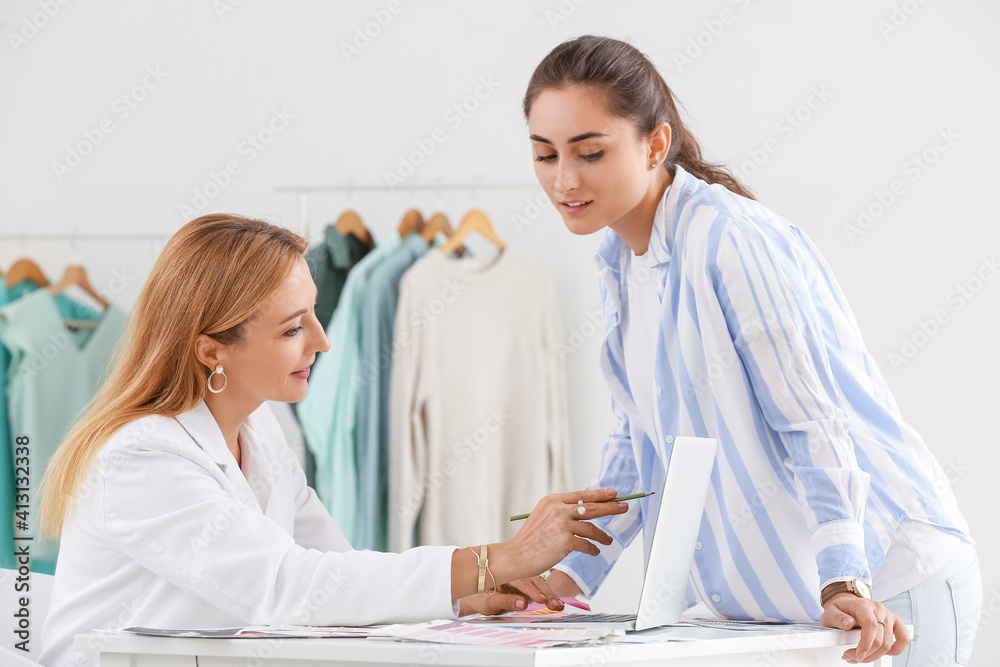 Female fashion designer and assistant working in studio Female fashion designer and assistant working in studio