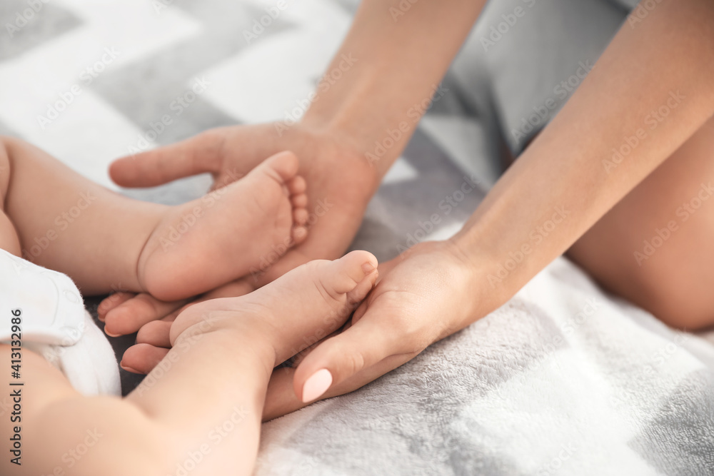 Mother holding feet of her little baby on bed Mother holding feet of her little baby on bed