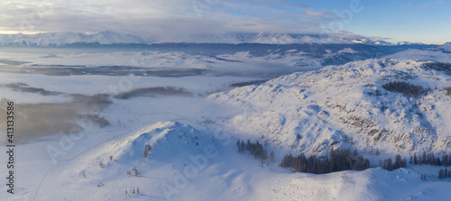 Panoramic aerial view of Kuray steppe and North Chuya Mountain Range in winter. Altai Republic, Siberia, Russia..